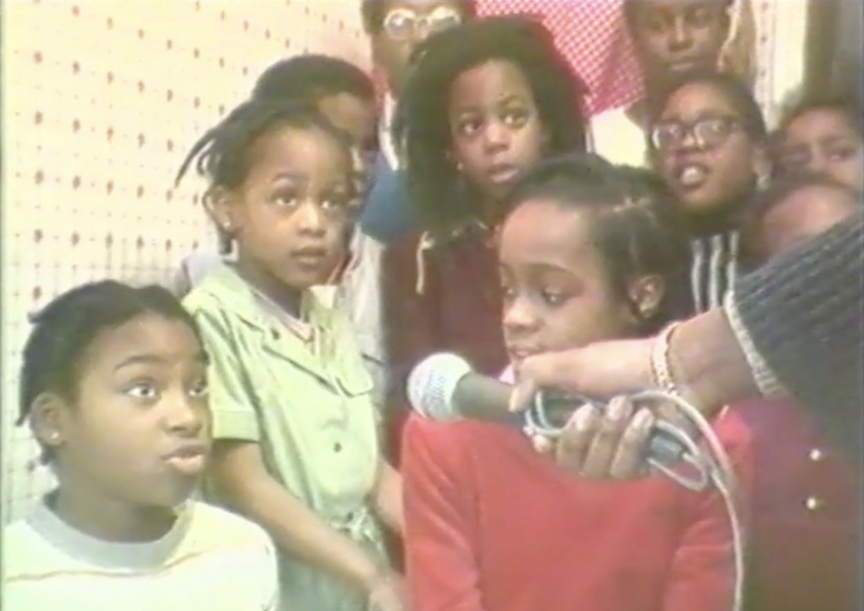 group of young kids with a hand holding a microphone.