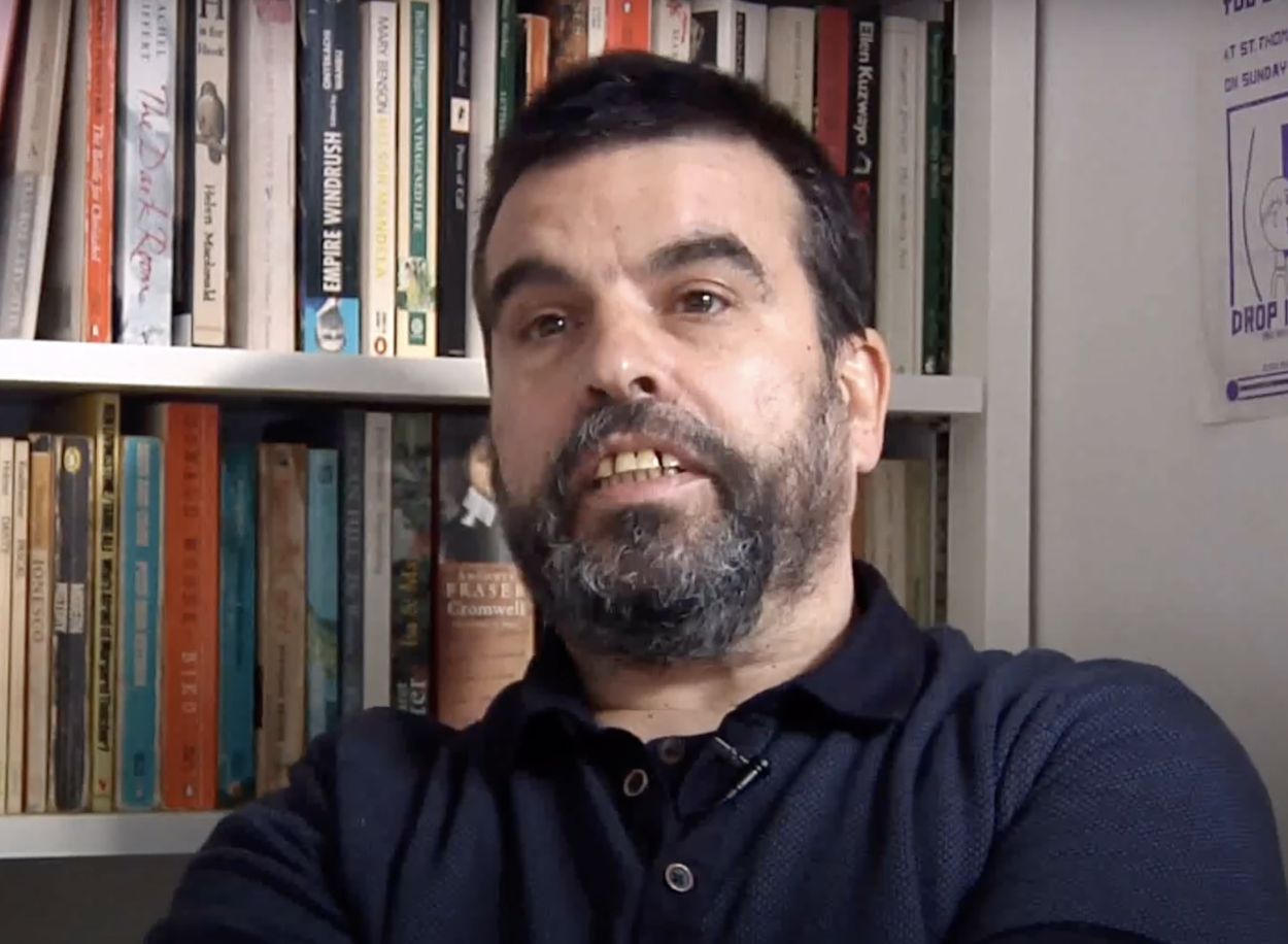 Alphonse Santana portrait in front on bookcase.